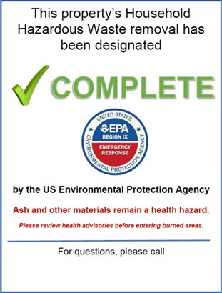 A sign that reads "This proeprty's Household Hazarous Waste removal has been designated Complete by the Environmental Protection Agency. Ash and other materials remain a health hazard. Please review health advisories before entering burn areas.