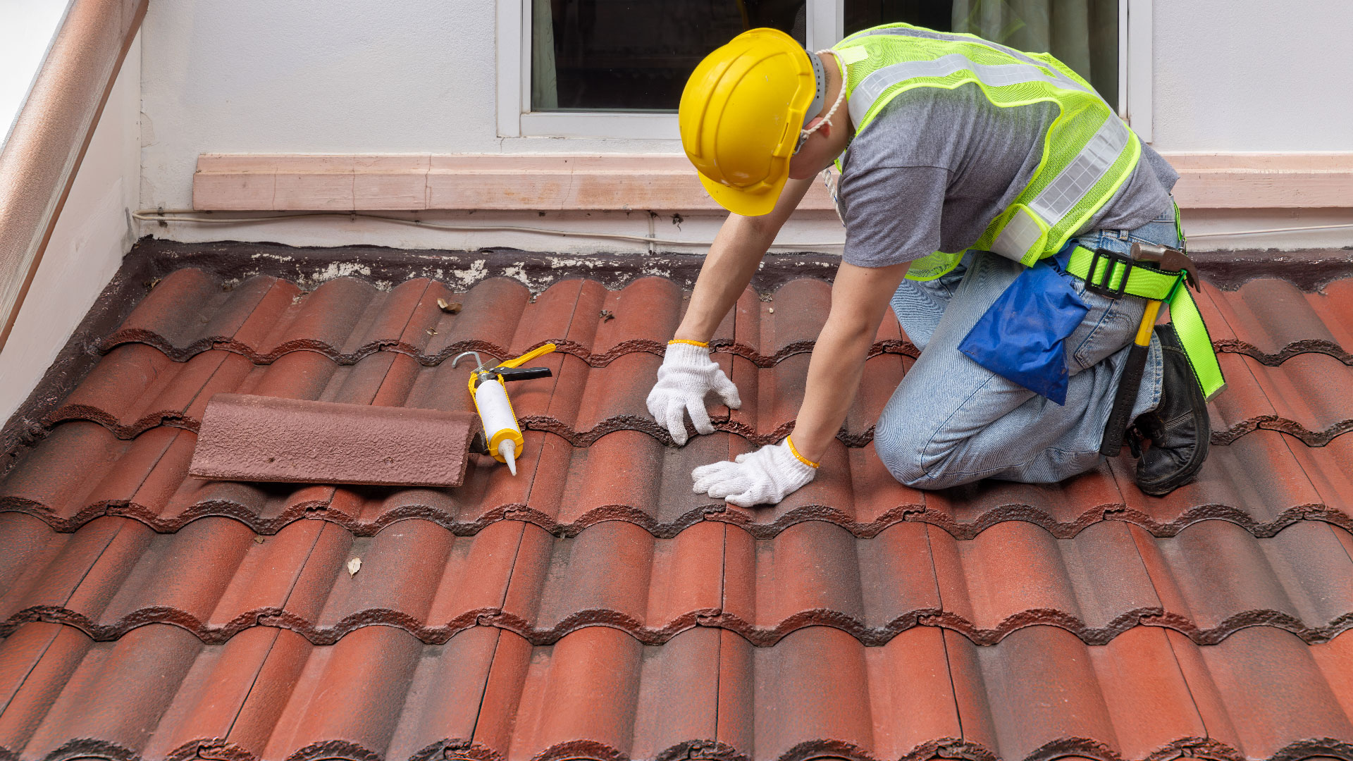 A construction worker installs tiles on roof.