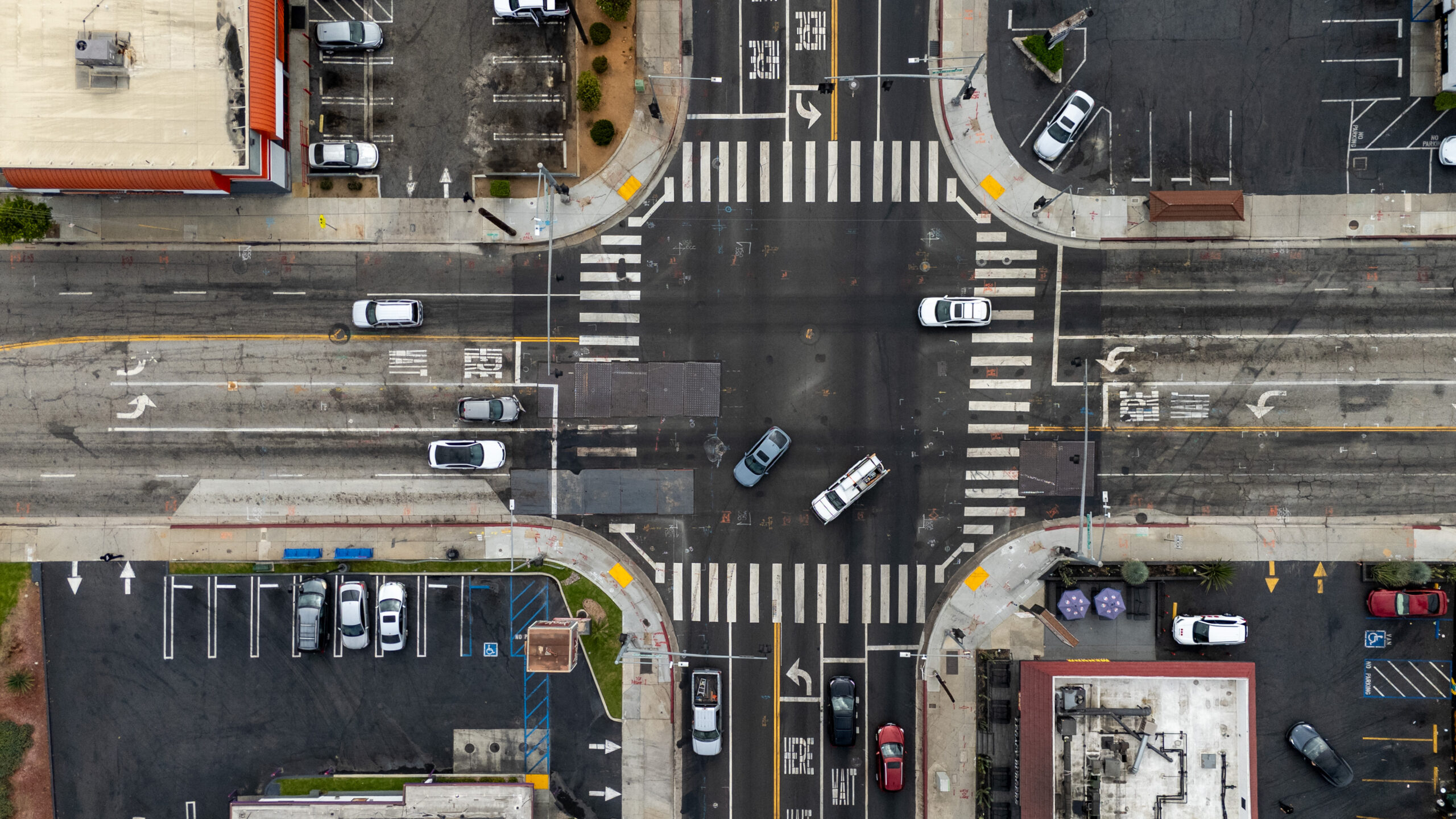 Ariel view on street intersection with vehicles driving, buildings, vehicles parked